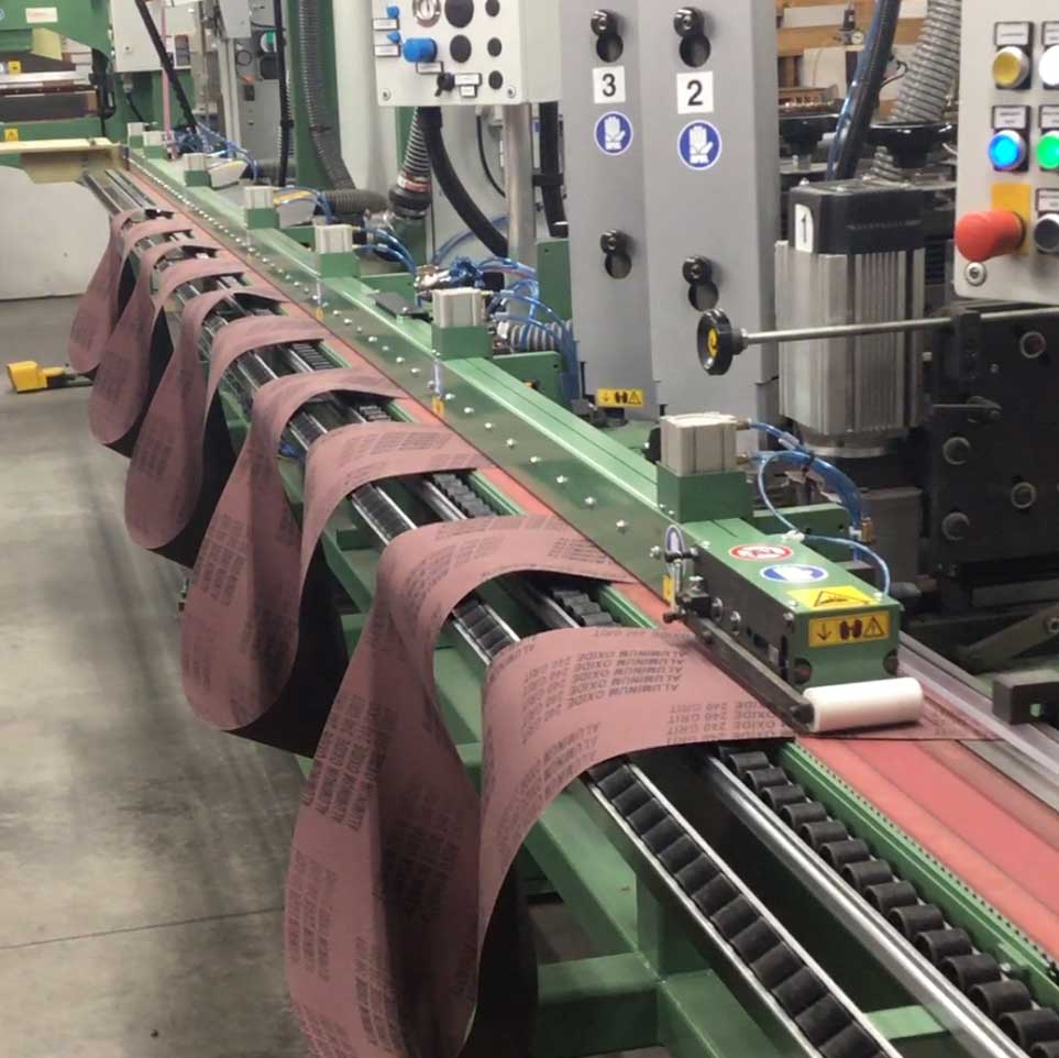 Automated belt fabrication is performed on a large machine.